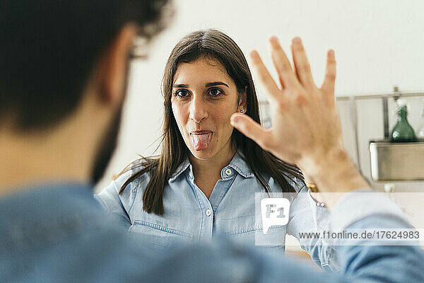 Woman sticking out tongue giving high-five to boyfriend at home