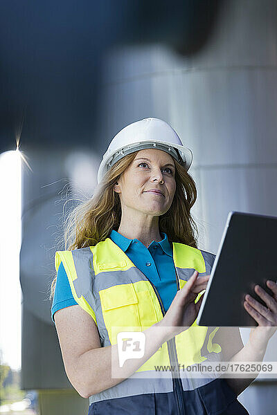 Technician wearing protective workwear using tablet PC in industry