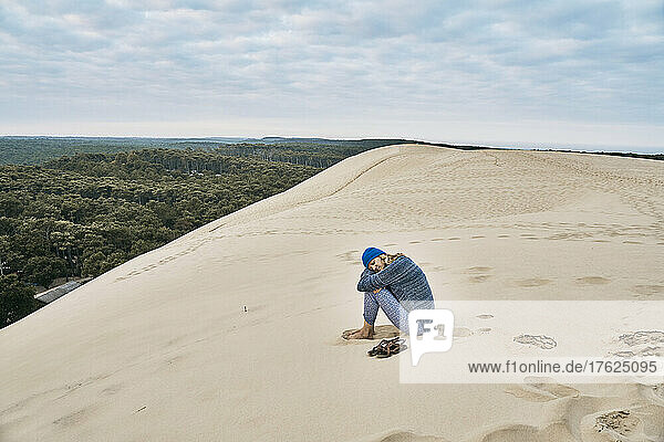 Woman sitting on sand dune at vacation