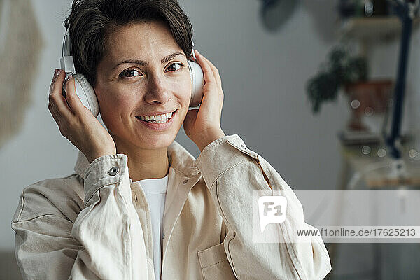 Smiling woman listening music through headphones