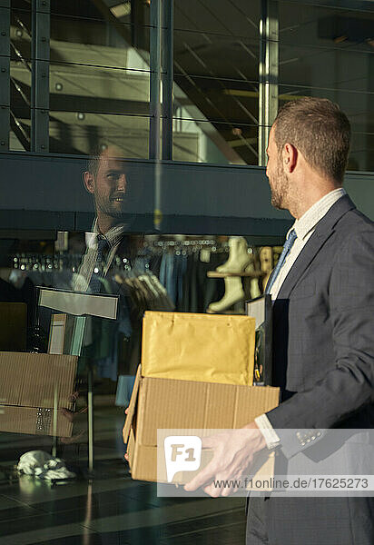 Businessman with box standing by office building
