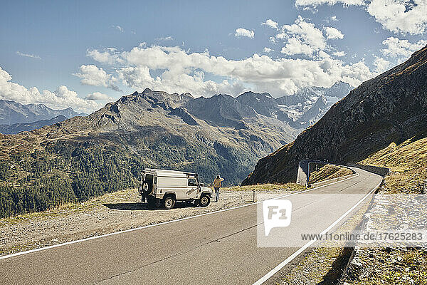 Woman standing by off-road vehicle on sunny day  Timmelsjoch Pass  South Tyrol  Italy