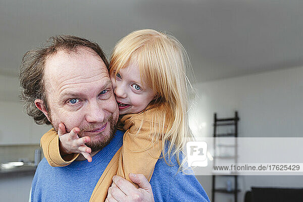 Playful blond girl with father at home