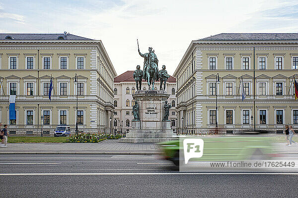 Germany  Bavaria  Munich  Car passing statue of Ludwig I of Bavaria standing in front of Bavarian State Ministry of Finance and Home