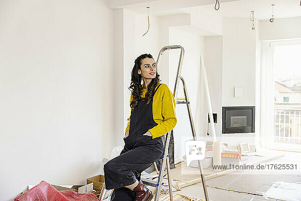 Contemplative woman sitting on ladder at new home