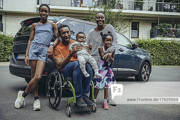 Cheerful disabled father with family at car