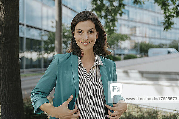 Happy businesswoman with smart casuals standing outside office building