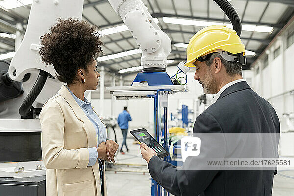 Engineer holding tablet PC standing with developer in factory