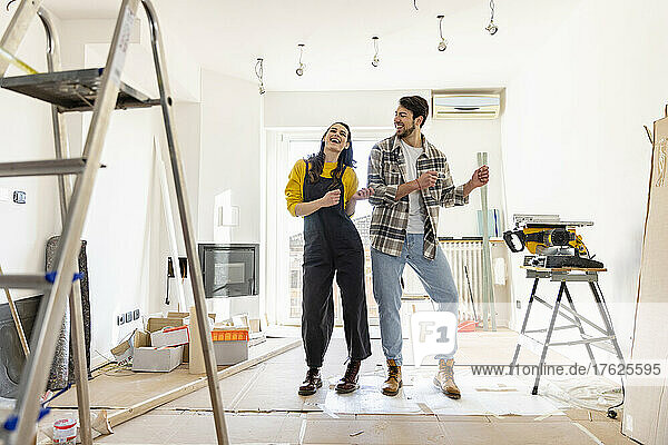 Fröhliches Paar renoviert sein Zuhause und tanzt im Wohnzimmer