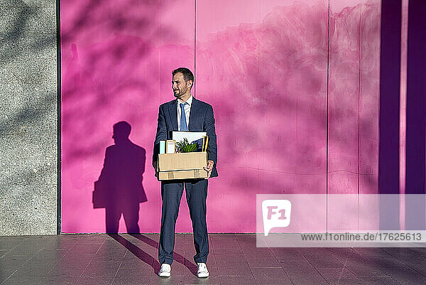 Geschäftsmann mit Kiste mit persönlichen Gegenständen auf Fußweg