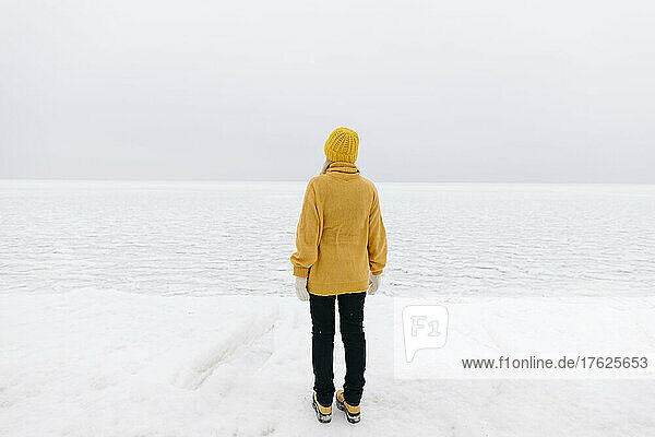 Woman standing by winter sea on weekend