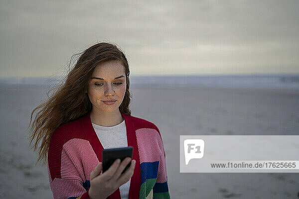 Junge Frau benutzt Smartphone am Strand