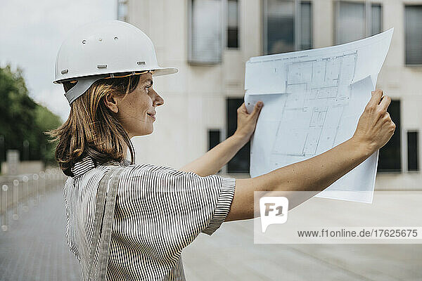 Architect with hard hat looking at blueprint