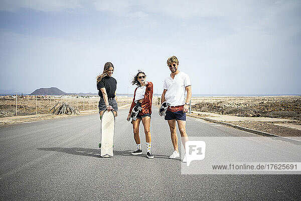 Friends with skateboards standing on road