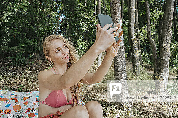Woman in bikini taking selfie on smart phone