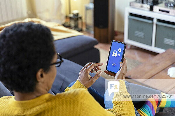 Frau nutzt App auf Smartphone im Wohnzimmer