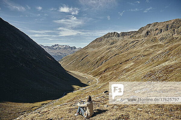 Tourist sitting on land by mountain at vacation  Timmelsjoch Pass  Otztal Alps  Austria