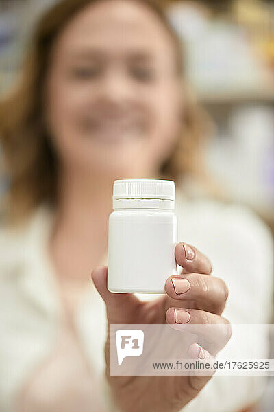 Pharmacist with bottle of medicine at pharmacy