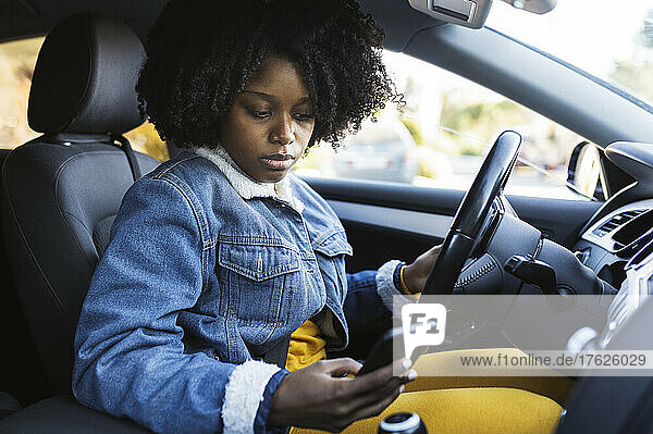 Young woman using mobile phone sitting in car