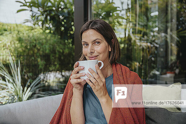 Lächelnde Frau mit Kaffeetasse im Hinterhof