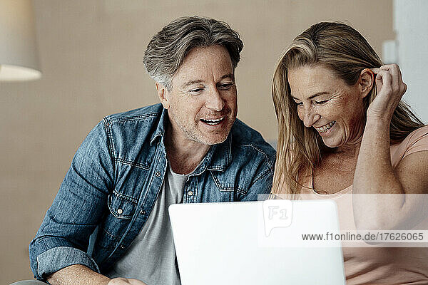 Cheerful couple using laptop at home