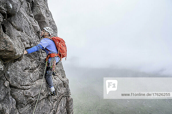 Man wearing helmet climbing rocky mountain