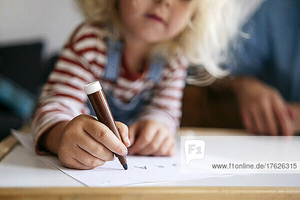 Junge zeichnet zu Hause mit Filzstift auf Papier