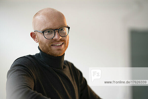 Smiling bald working man wearing eyeglasses in office