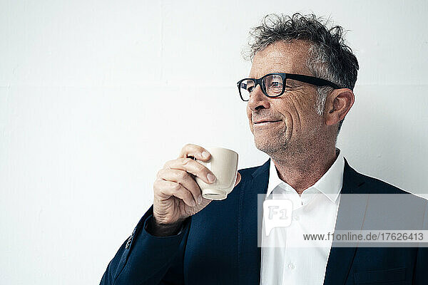 Smiling businessman having coffee against white background