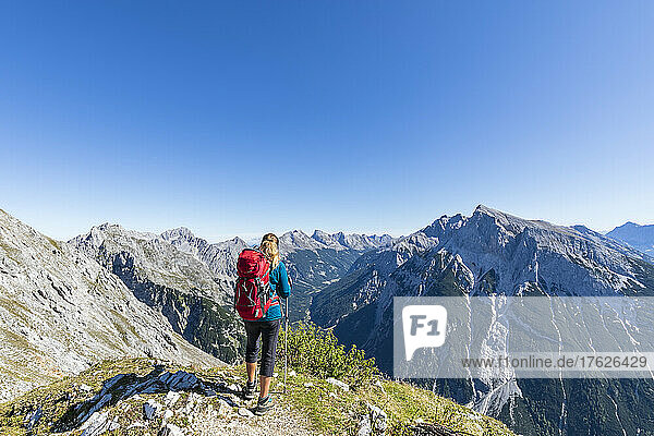Female hiker admiring view of Mittenwalder Hohenweg in summer