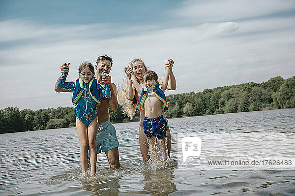 Cheerful parents with children standing in lake on weekend