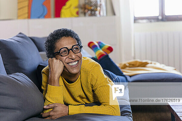 Smiling woman day dreaming on sofa in living room