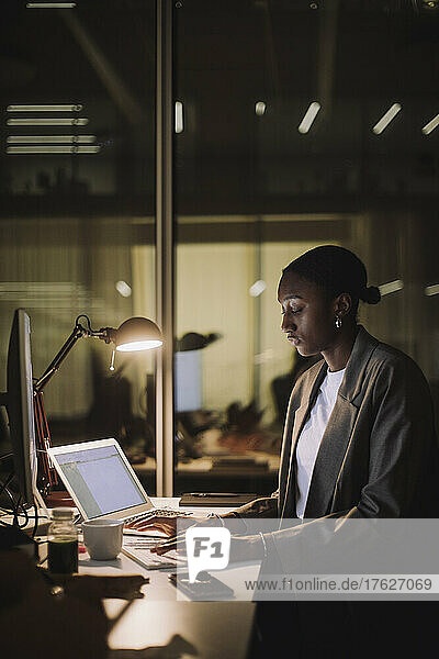 Ehrgeizige berufstätige Frau mit Laptop am Schreibtisch im Büro