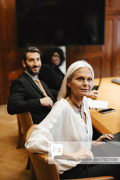 Multirassische weibliche und männliche Kollegen sitzen am Konferenztisch im Sitzungssaal während einer Sitzung