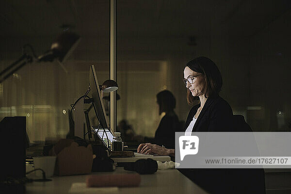 Geschäftsfrau konzentriert sich bei der Arbeit am Laptop im Büro bei Nacht