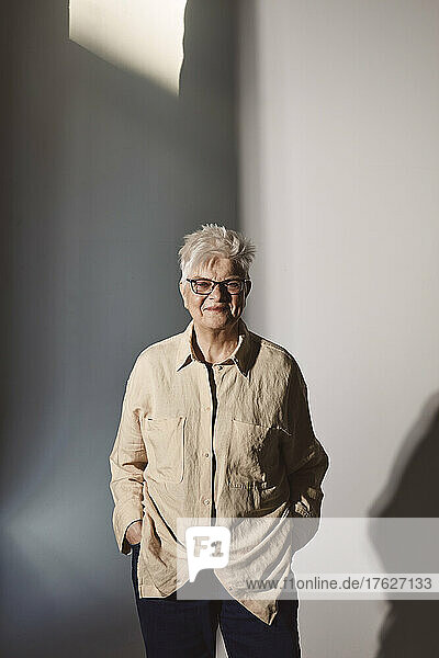 Porträt einer älteren Frau mit Händen in den Taschen im Atelier