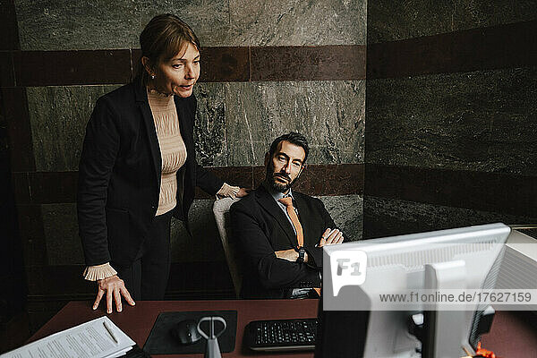 Businesswoman and businessman staring at computer monitor at law office