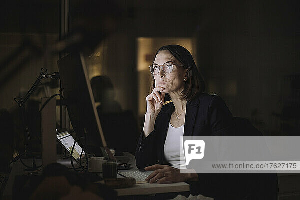 Ambitious businesswoman working overtime on computer in office at night