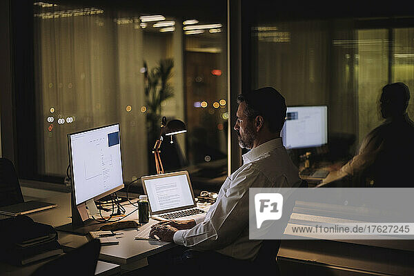 Businessman typing on computer keyboard while working in office at night