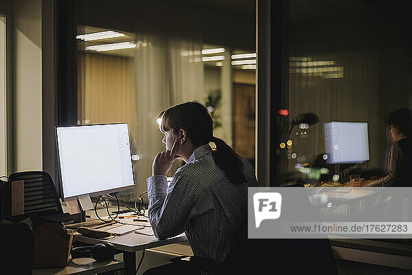Junge Geschäftsfrau konzentriert sich bei der Arbeit am Computer im Büro bei Nacht