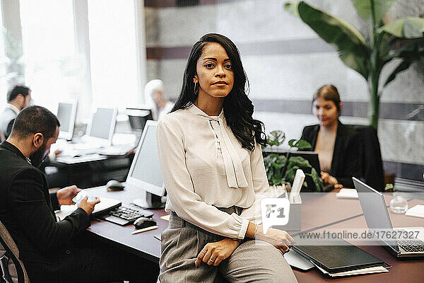 Porträt einer selbstbewussten Geschäftsfrau  die in einer Anwaltskanzlei am Schreibtisch sitzt