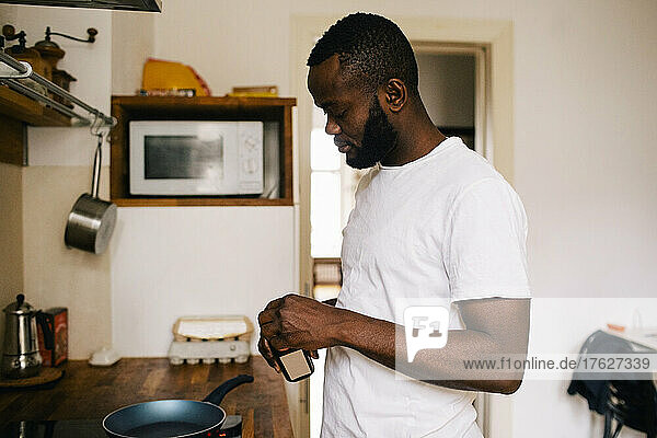Seitenansicht eines depressiven Mannes beim Kochen in der Küche zu Hause