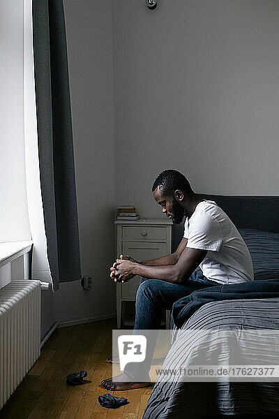 Volle Länge Seitenansicht der depressiven einsamen Mann sitzt auf dem Bett zu Hause