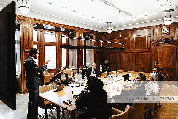 Ein Team von Anwälten bespricht sich mit einem Geschäftsmann im Sitzungssaal während einer Konferenz