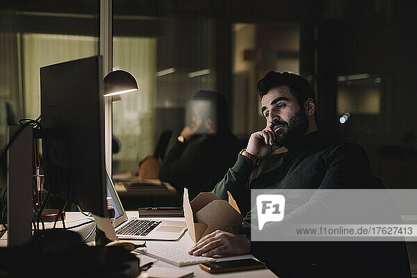 Businessman working on computer last minute in office at night