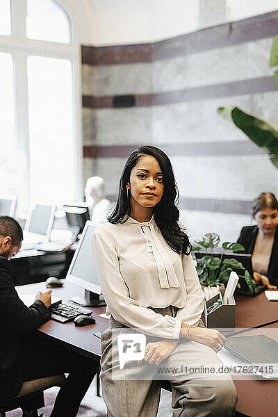 Porträt einer selbstbewussten Finanzberaterin  die in einer Anwaltskanzlei am Schreibtisch sitzt