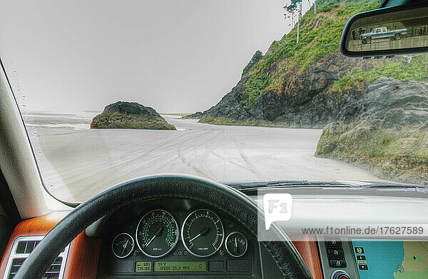 Beach seen from driver's seat of a car  with steering wheel in foreground.