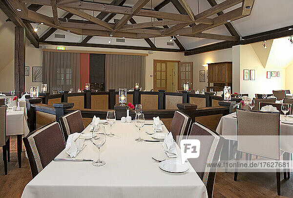 Dining room  tables laid for dinner on a mezzanine floor  exposed beams and vaulted ceiling.