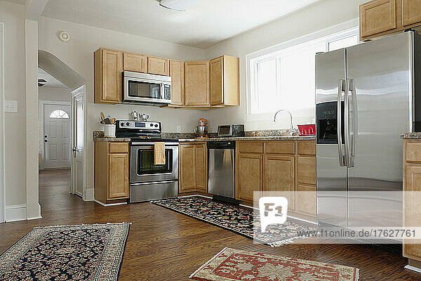 Fitted kitchen in a modern home  ovens and integrated appliances  fridge and rugs on a wood floor