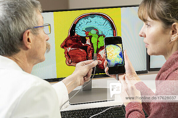 Researcher explaining to a woman how one will soon be able to plug his cell phone directly into the brain.